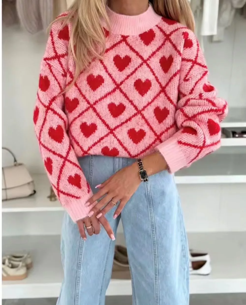 Primo piano sul maglione donna rosa con motivo a cuori rossi indossato con jeans chiari