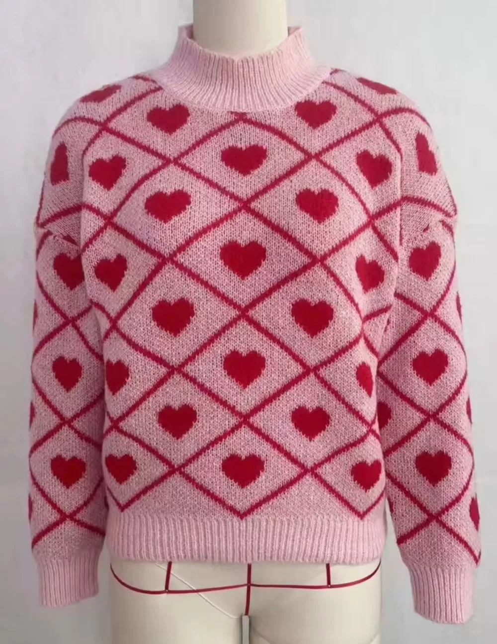 Maglione donna rosa con motivi a cuori rossi su manichini, vista frontale