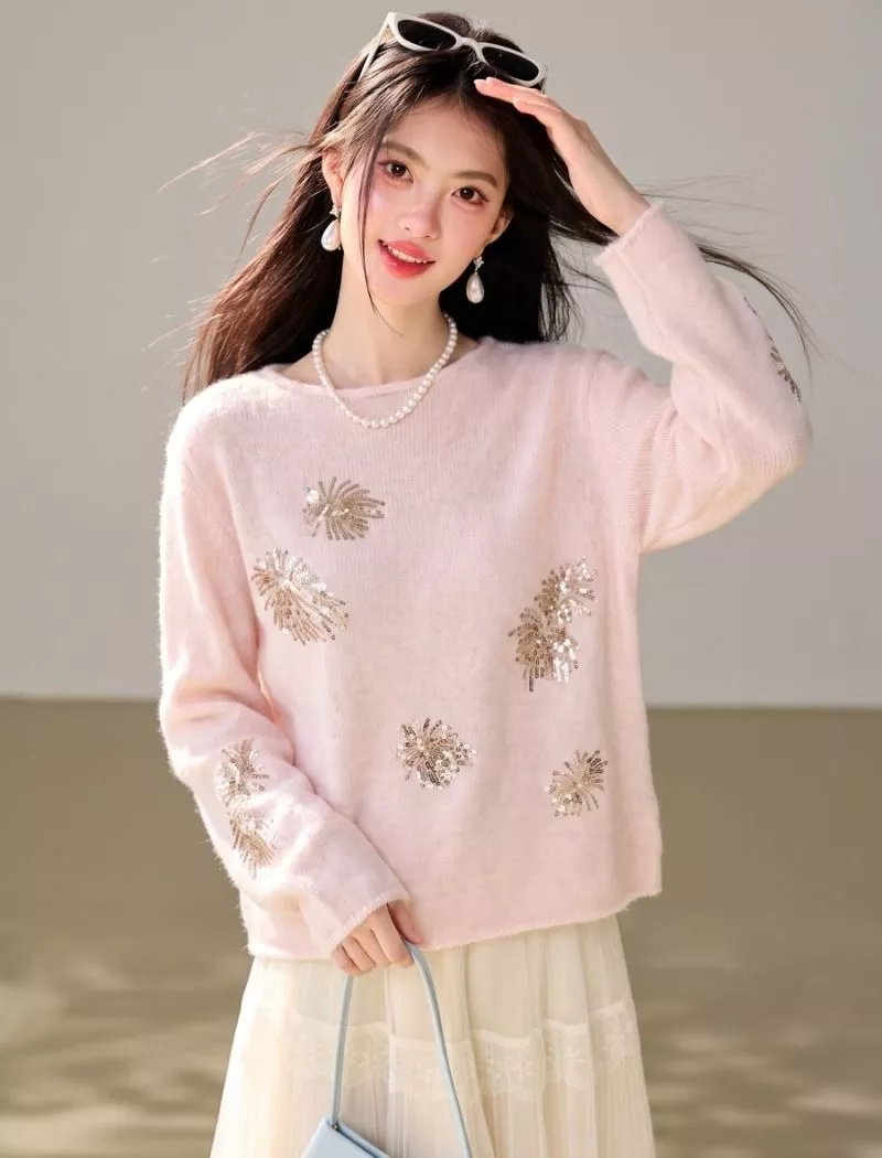 Particolare del maglione rosa con decorazioni luminose indossato con gonna chiara