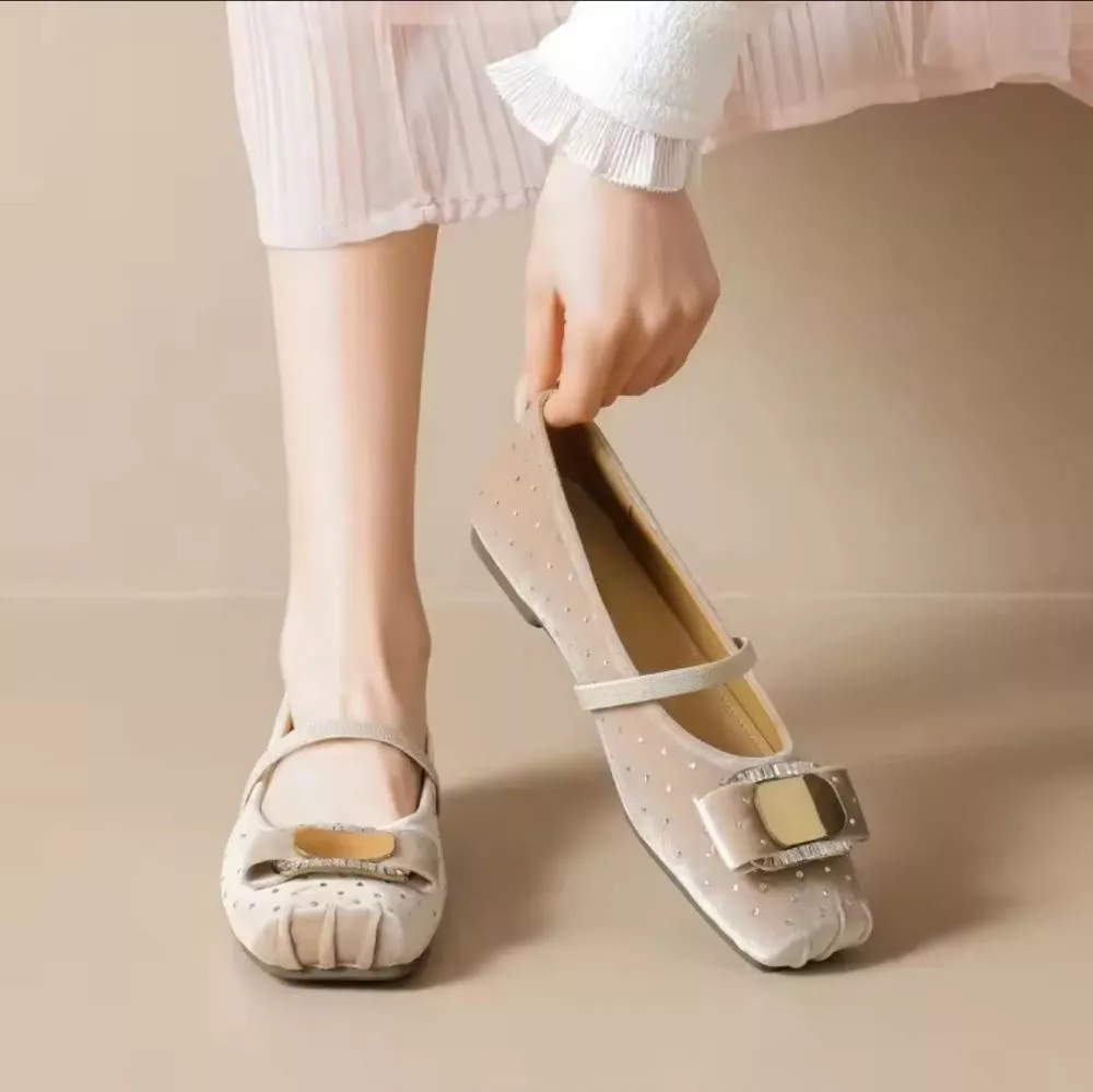 Mocassini beige donna con cinturino e fibbia lucida, posizionati su superficie bianca