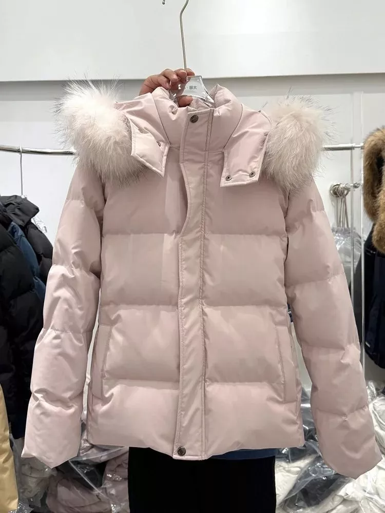 Piumino donna rosa chiaro con cappuccio e pelliccia sintetica appeso