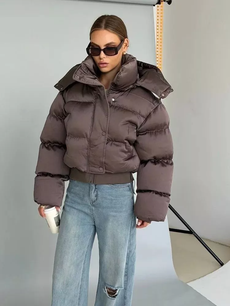 Donna con piumino corto marrone, collo alto e zip, indossa jeans chiari