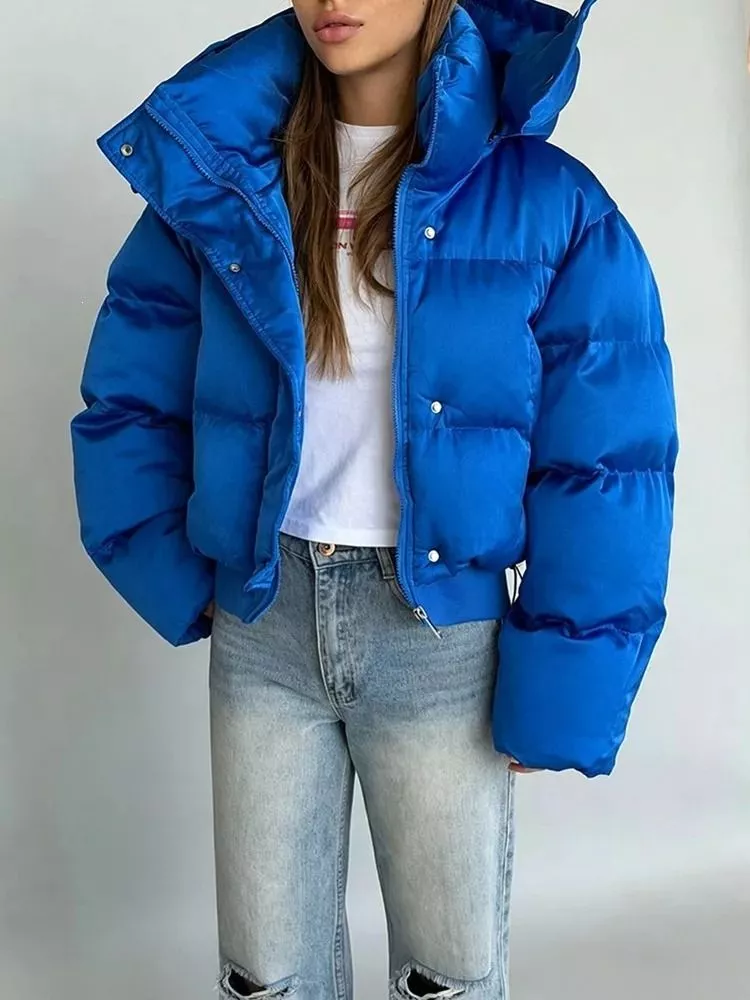 Donna con piumino corto blu elettrico con collo alto, abbinato a jeans chiari