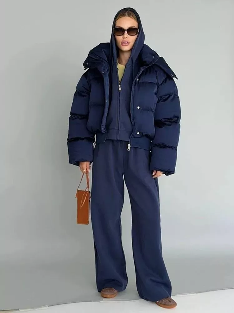 Donna con piumino corto blu navy con cappuccio indossato sopra tuta