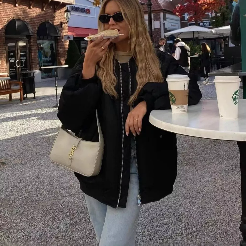 Donna con piumino nero oversize, maniche ampie a sbuffo, cappuccio e zip centrale